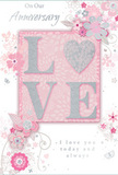 This photograph captures a romantic anniversary card designed in soft, dreamlike tones that echo a spring morning in Belvedere. The eye is first drawn to the central word LOVE, embossed in raised letters that have been delicately edged with pale, shimmering glitter. The glitter adds a subtle sparkle, reminiscent of sunlight catching dewdrops on flowers in a local Belvedere garden. The letters rest on a blush-pink background panel that appears slightly inset, creating a framed effect. Around this, an airy wreath of illustrated flowers winds across the card. The blooms are rendered in blush, mauve, and pearly white, their petals outlined with whisper-thin lines and accented with hints of silver, as if sketched by a florist planning an anniversary arrangement for same-day delivery. Soft curling vines and leaves link each blossom to the next, forming a flowing pattern that stretches towards the corners like the natural spread of a bouquet laid out on a workbench. Sprinkled throughout are tiny decorative touches-swirling flourishes, single petals, and little butterflies-that add movement and a playful, romantic energy, suggesting a breeze stirring petals along a garden path by Abbey Park. The background fades gently from pale pink to near-white, giving the whole card an airy, light-filled atmosphere. In elegant, understated script above and below the main motif are anniversary sentiments, including the phrase On Our Anniversary and a promise of enduring love. The composition feels intimate and heartfelt, capturing the quiet joy of years spent together and the tenderness of a carefully chosen card exchanged at home in Belvedere.